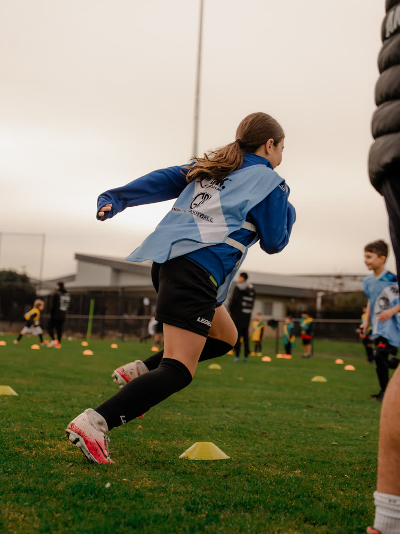A girl running with the ball at a GDF session